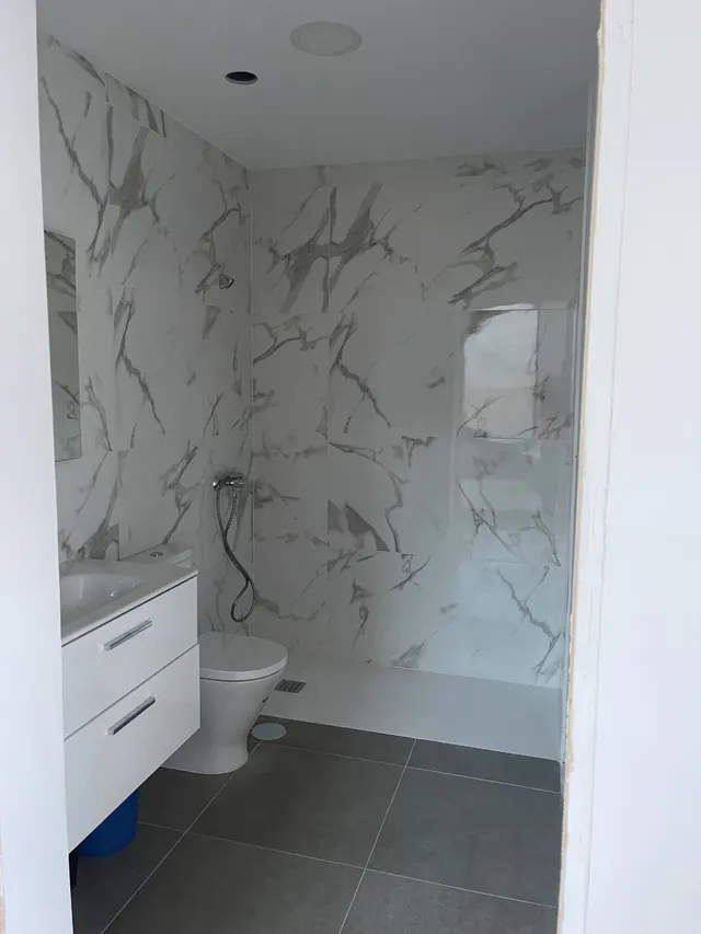 Instalación de azulejos blancos y gris en el baño