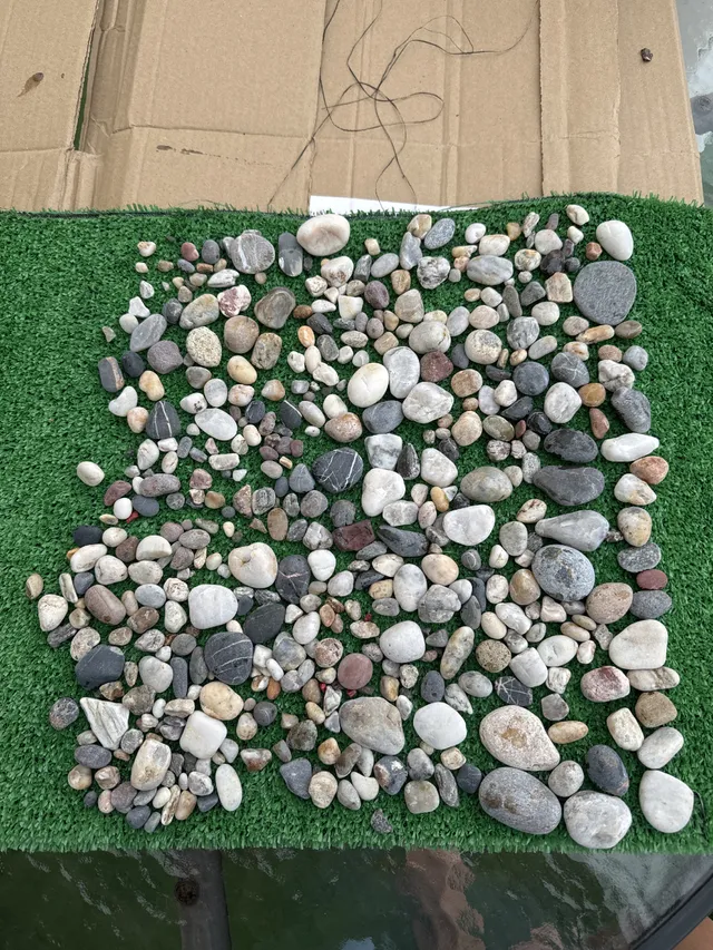 ¿Qué producto puedo utilizar  para pegar estas piedras al césped artificial para hacer una alfombra de piedras ?