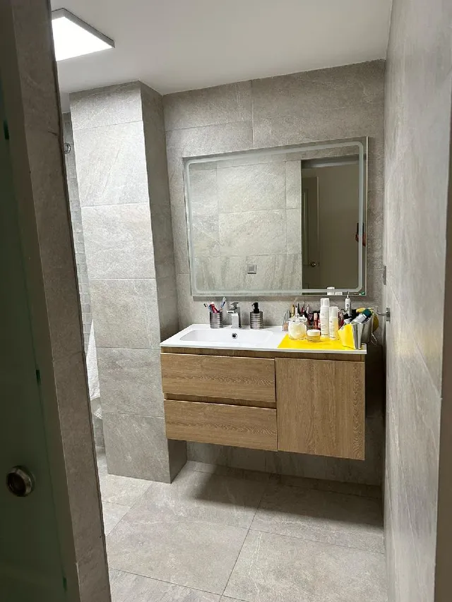Reforma de baño con cerámica en tonos grises y lavabo suspendido de madera