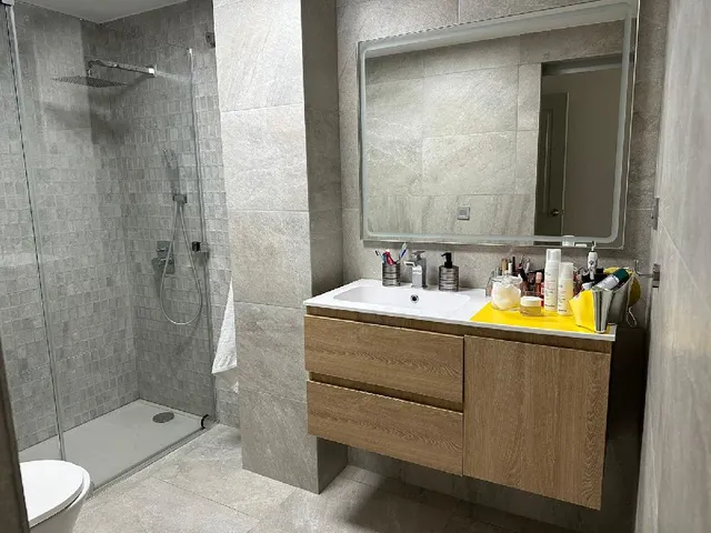 Reforma de baño con cerámica en tonos grises y lavabo suspendido de madera
