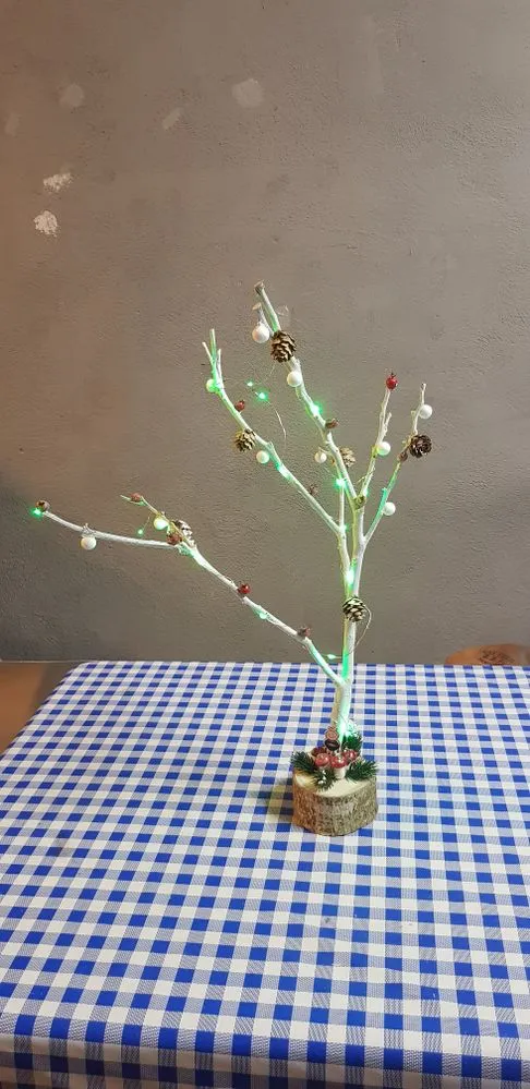 Pequeño árbol navideño de rama de naranjero y base de madera de nogal