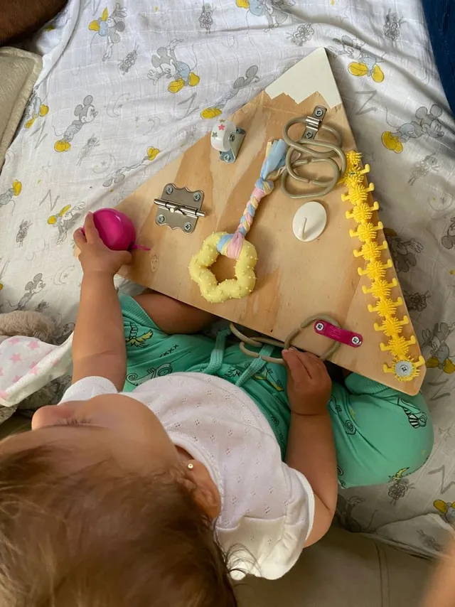 Así de feliz está ella jugando con su tabla sensorial DIY
