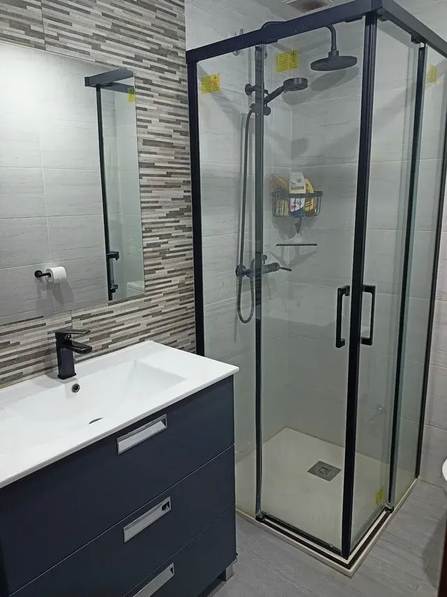 Una reforma total de baño con toques en negro y azulejos blancos y marrones